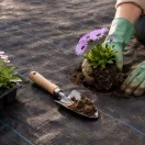 Talajtakaró geotextília, MultiGarden WEED135-M2, 1,1 x 50 m, fekete, nem szőtt, 135 g/m2, tekercs, polipropilén, víz- és légáteresztő, kék vezetőcsíkokkal, 50 db rögzítő tüskével (15 cm)